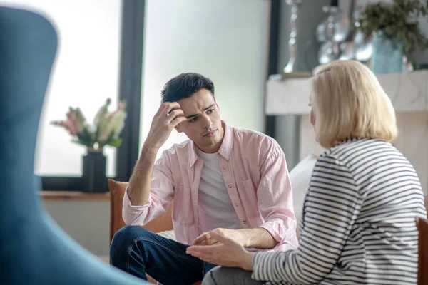 Junger Mann im rosa Hemd sieht zweifelnd und unsicher aus — Stockfoto