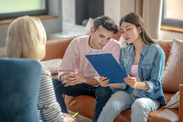 Donkerharige lange man zit naast zijn vriendin iets te lezen — Stockfoto