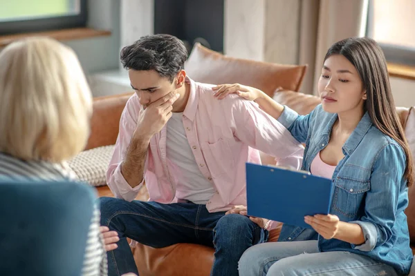 Donkerharige lange man zit naast zijn vriendin kijken gestresst — Stockfoto