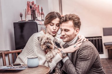 Mutlu çift aralarında küçük köpeğe sarılıyor.