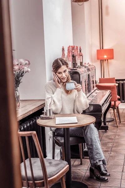 Genç ve güzel bir bayan kafede oturup kahve içiyor. — Stok fotoğraf
