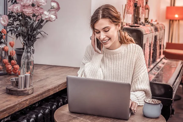 Mujer joven atractiva usando el ordenador portátil y el teléfono en la cafetería — Foto de Stock