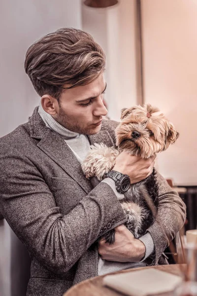 Retrato de un hombre guapo abrazando a un perro pequeño a su pecho — Foto de Stock