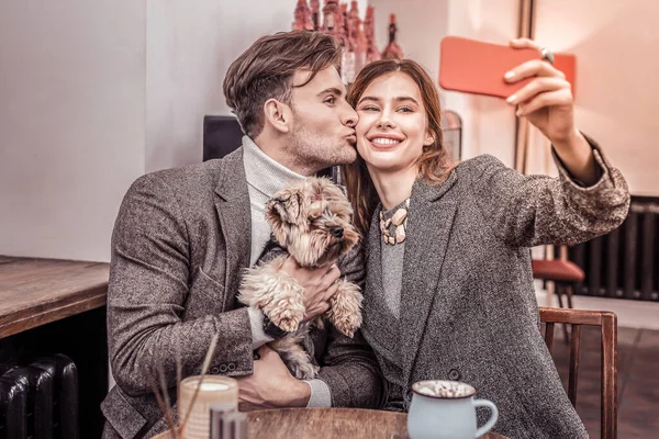 Alegre pareja sentado en café tomando selfies con perro —  Fotos de Stock