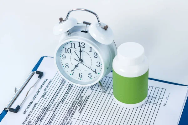 White alarm clock and pills bottle on the table — Stock Photo, Image