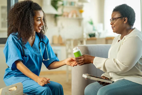 Thankful aged woman taking pills from a caring medical attendant — Stock Photo, Image