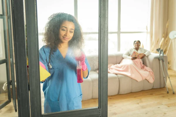 Profissional jovem enfermeira limpeza seus pacientes apartamento — Fotografia de Stock