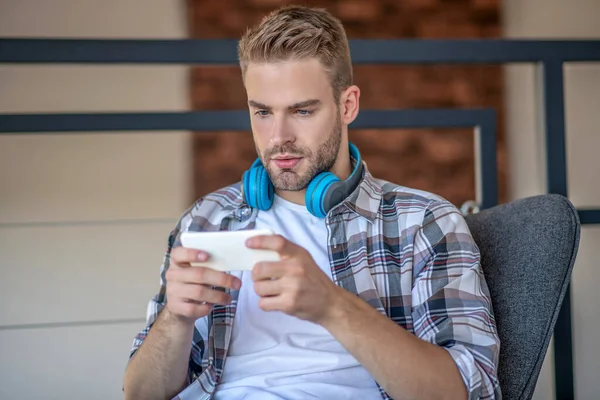 Junger Mann im karierten Hemd hält sein Smartphone — Stockfoto