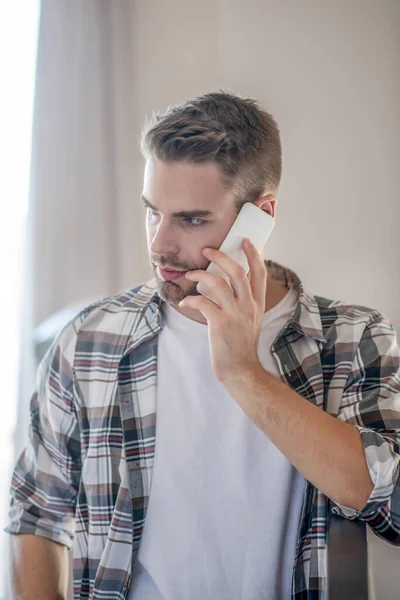 Νεαρός με καρό πουκάμισο να μιλάει στο τηλέφωνο. — Φωτογραφία Αρχείου