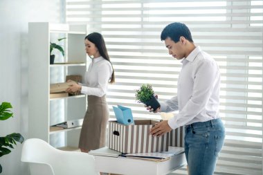 Genç, esmer, erkek şahsi eşyalarını kutuya koy.