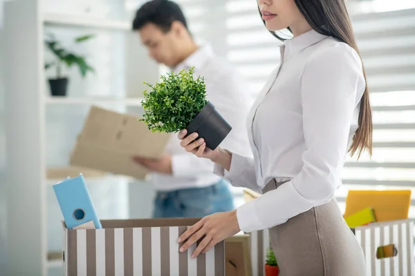 Brunette vrouw staat aan haar bureau, zet haar persoonlijke spullen in doos — Stockfoto