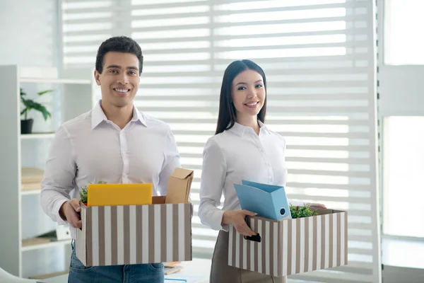 Man en vrouw die hun kantoorkastjes vasthouden en er gelukkig uitzien — Stockfoto