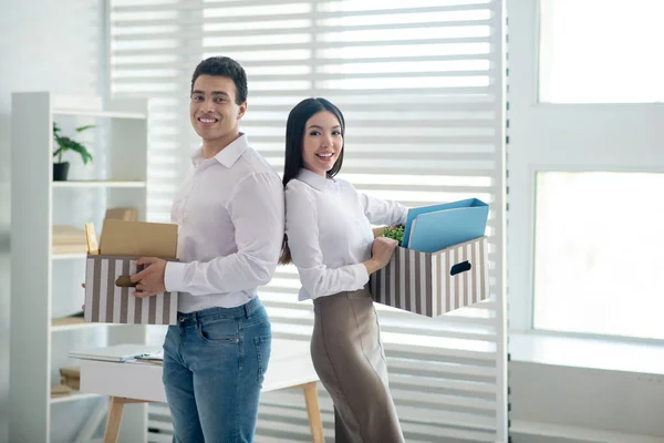 Duas pessoas segurando caixas com material de escritório e sorrindo — Fotografia de Stock
