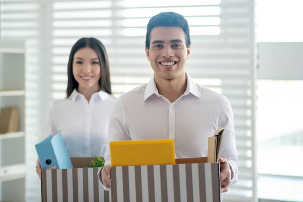 Dos colegas sosteniendo cajas con cosas de oficina y sonriendo — Foto de Stock