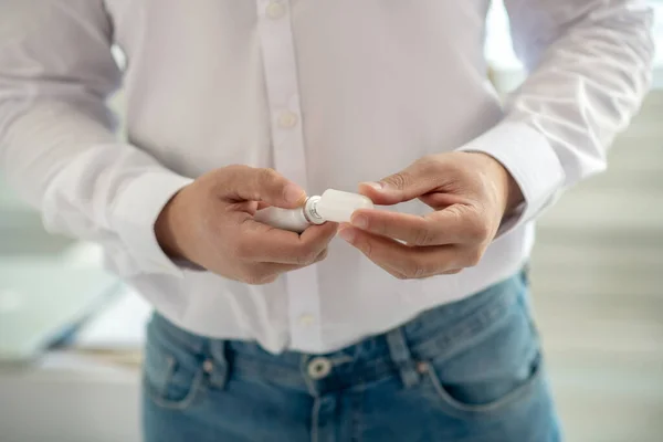 Hombre con una camisa blanca sosteniendo un desinfectante en su mano — Foto de Stock