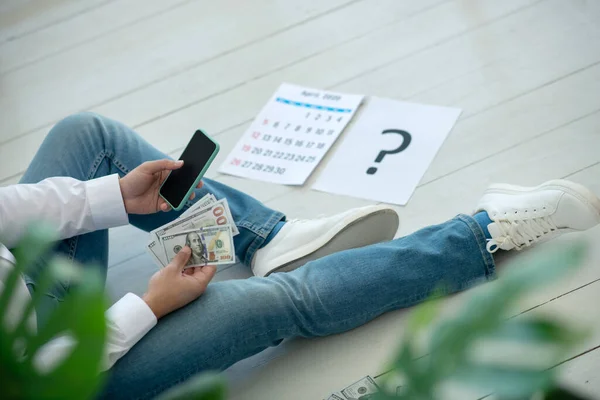 Hombre sentado en el suelo y pensando dónde conseguir dinero —  Fotos de Stock