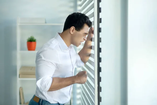 Mann schaut aus dem Fenster und sieht gestresst aus — Stockfoto