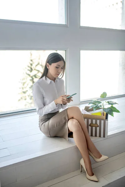 Langharige vrouw in een witte blouse leest berichten — Stockfoto