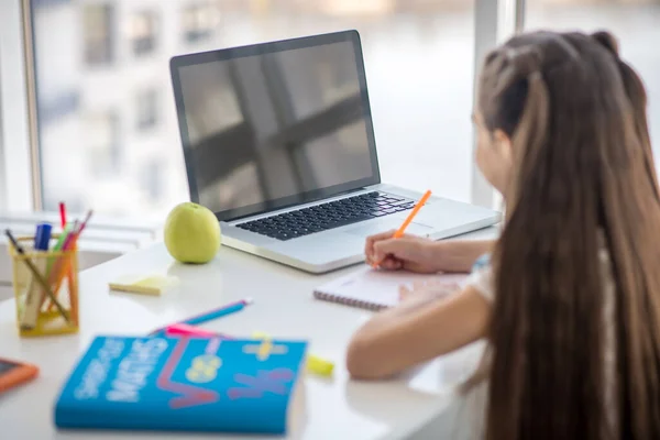 Mädchen schaut zu Hause am Tisch auf Laptop-Bildschirm. — Stockfoto