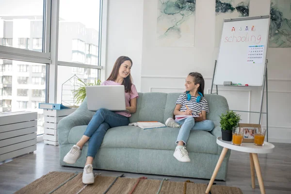 Mamá e hija sentadas en el sofá en casa . — Foto de Stock