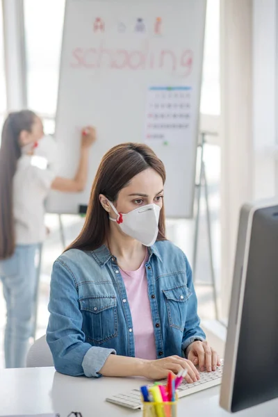 Frau mit Schutzmaske arbeitet am Computer. — Stockfoto