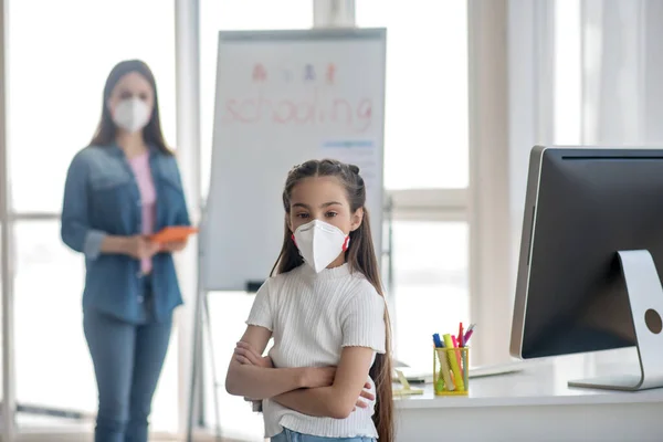 Skolflicka i skyddsmask, kvinna bakom. — Stockfoto