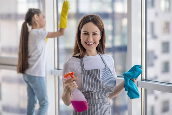 Satisfied happy mom and daughter washing a window. — Stock Photo, Image