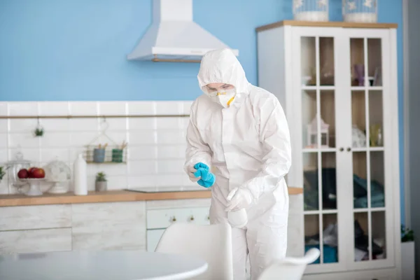 Жінка в білому робочому одязі робить дезінфекцію в квартирі — стокове фото