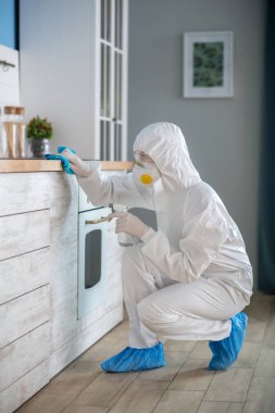 Woman in white workwear and protective gloves disinfecting the room clipart