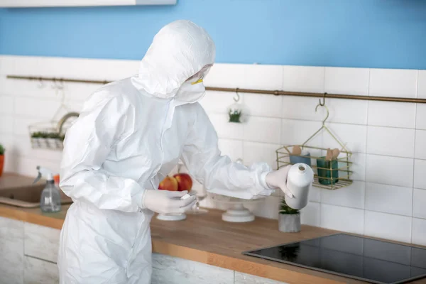 Жінка в білому робочому одязі і рукавичках дезінфікує кухню — стокове фото