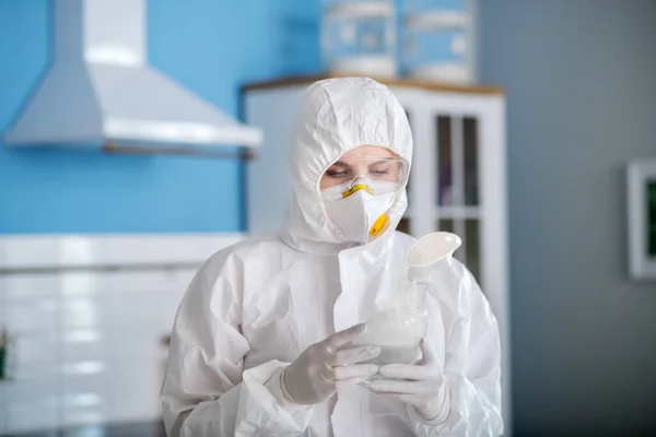 Osoba v bílém pracovním oděvu a rukavicích držící antiseptika v rukou — Stock fotografie