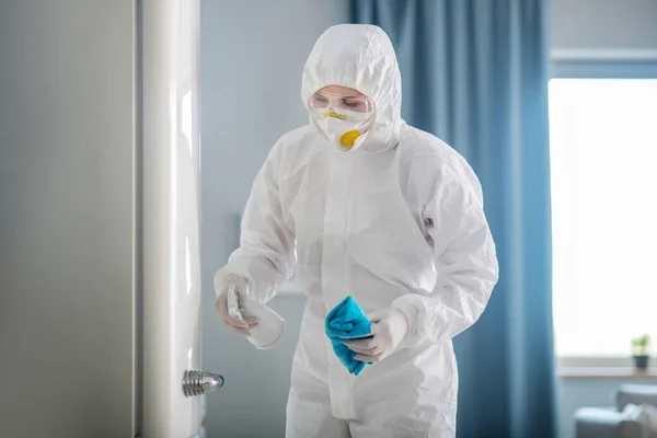 Людина в білому робочому одязі і рукавичках дезінфікує поверхню холодильника — стокове фото
