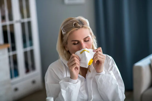 Blond kvinna i vita arbetskläder bär respirator — Stockfoto