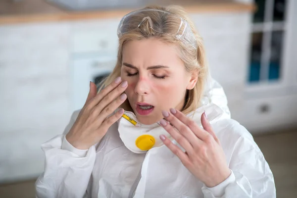 Блондинка в рабочей одежде, страдающая аллергией — стоковое фото