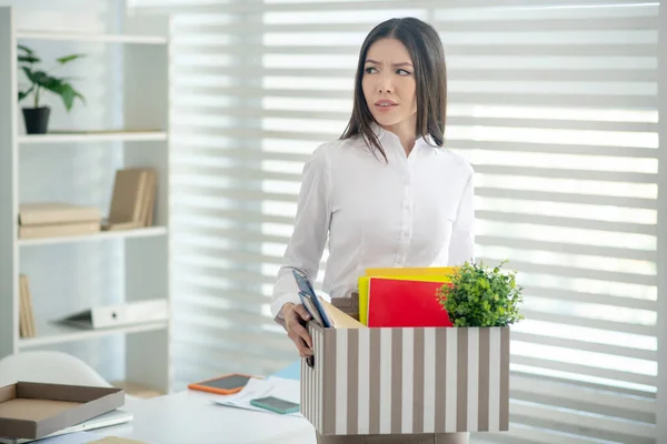 Overstuur jong brunette vrouw holding box met haar persoonlijk spul — Stockfoto