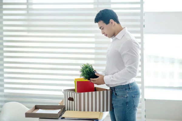 Morena macho de pie en su escritorio, poniendo sus cosas personales en la caja — Foto de Stock