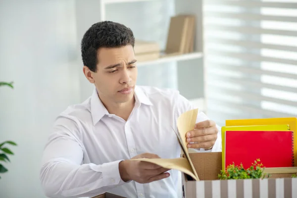 Brunette man zit aan zijn bureau, enveloppen in de doos met zijn persoonlijke spullen — Stockfoto