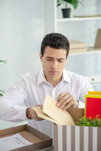 Van streek brunette man zitten aan zijn bureau, het zetten van enveloppen in de doos met zijn persoonlijke spullen — Stockfoto