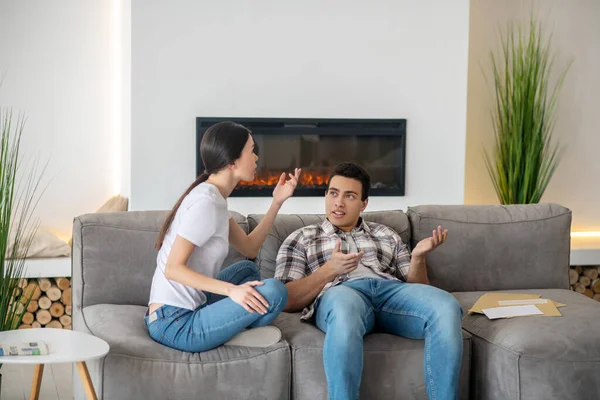 Brunette male and dark-haired female sitting on sofa, arguing about something — Stock Photo, Image