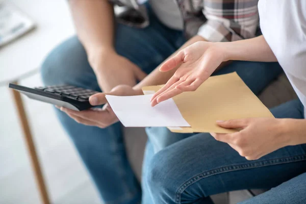 Närbild av manliga och kvinnliga händer håller miniräknare och kuvert — Stockfoto