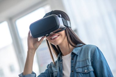 Siyah saçlı, kulaklık takan ve gülümseyen bir kız.