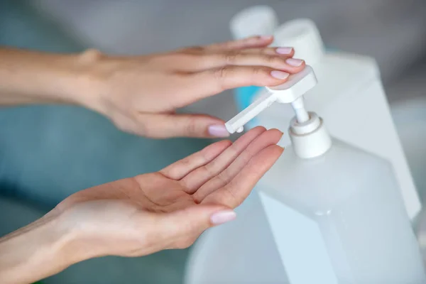 Imagen de cerca de manos humanas exprimiendo antiséptico de la botella — Foto de Stock