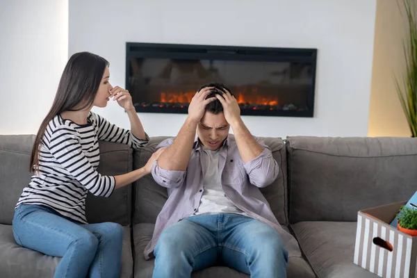 Jovem segurando sua cabeça e sua esposa . — Fotografia de Stock