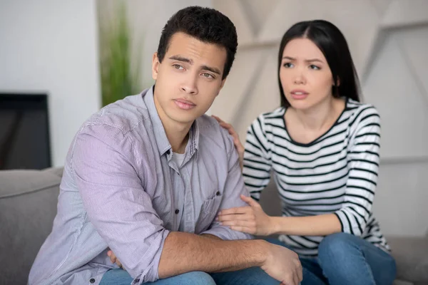 Joven chico ansioso y chica sentada en un sofá . — Foto de Stock