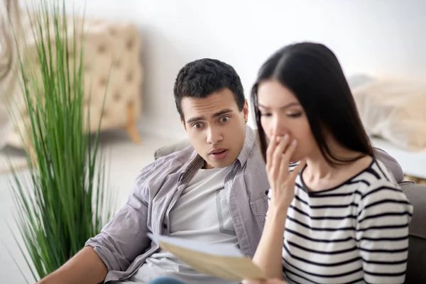 Sorprendido joven esposa y marido leyendo un documento . — Foto de Stock