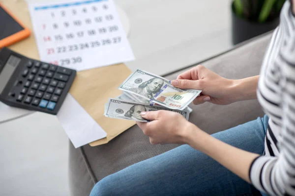 Kvinnliga händer håller pengar sedlar nära en miniräknare. — Stockfoto