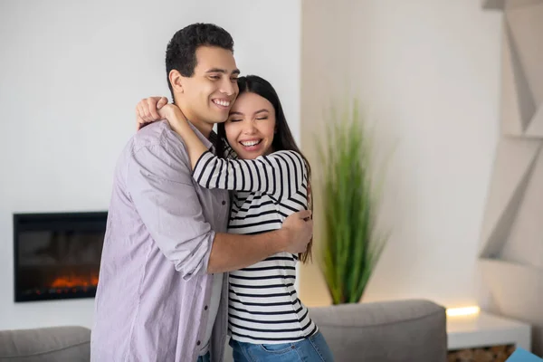 Счастливые молодые мужчина и женщина обнимаются дома . — стоковое фото