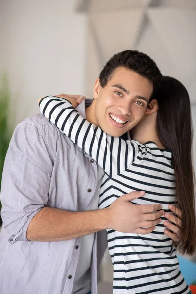 Ung man med vitt tandat leende kramar en kvinna. — Stockfoto