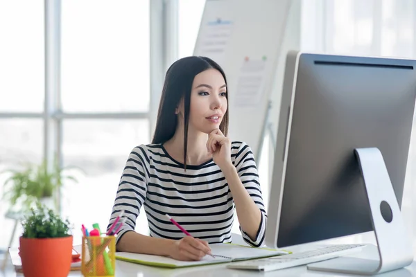 Donkerharige mooie vrouw in een gestreept shirt ziet er serieus uit — Stockfoto