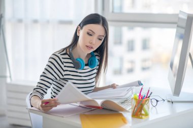 Güzel esmer kadın gazetelerle çalışıyor ve ilgili görünüyor.